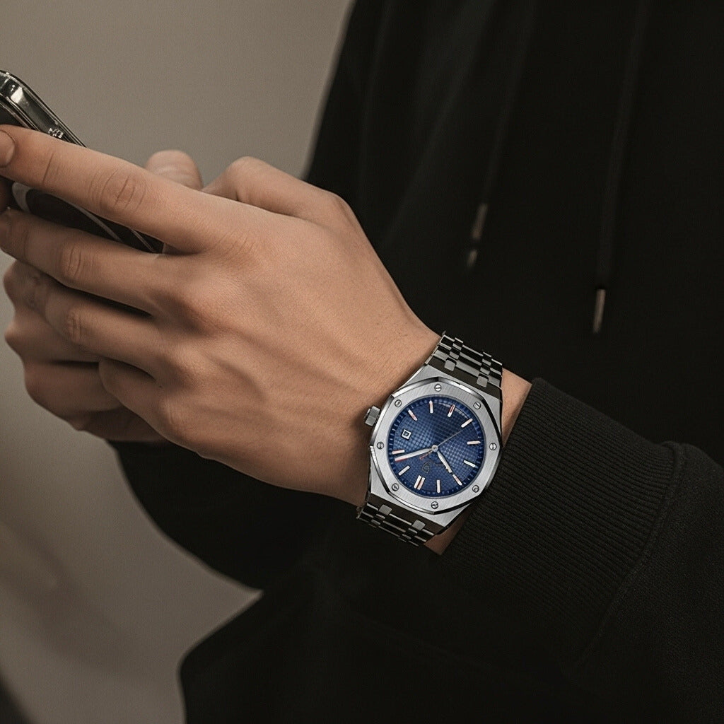 Person wearing a watch with a blue face, holding a phone, on a neutral background. Luxury Old money style
