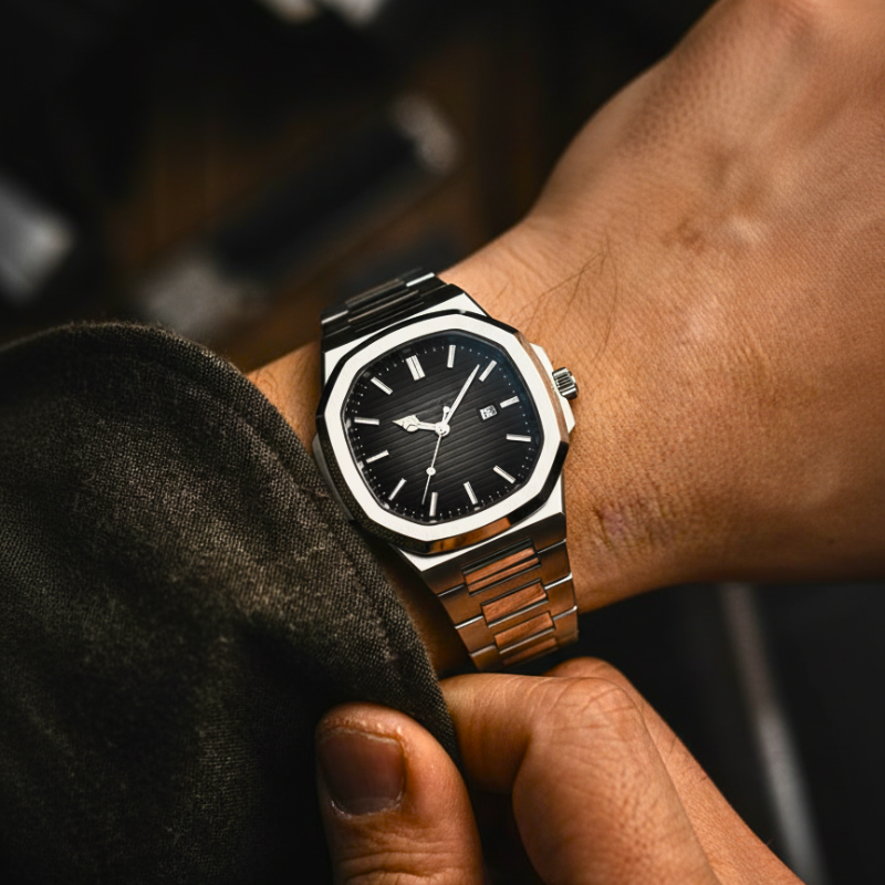 Close-up of a wrist wearing a black and gold watch with a blurred background